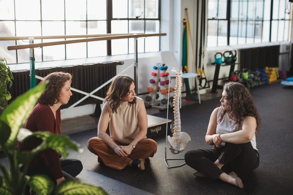 Three Foundations therapists reviewing anatomy together with a spine and pelvis model